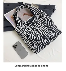 Größenvergleich zwischen einer großen Zebra-Canvas-Tasche und einem Smartphone