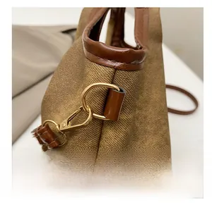 Detail of vintage canvas tote showing gold metal hooks and dark brown leather stitching