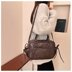 Detail view of vintage dark brown faux leather boston bag with side strap and gold hardware