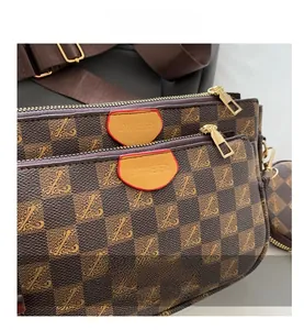 Close-up of checkerboard patterned crossbody bag with golden zippers and leather brand tag