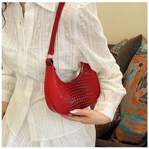 Détail de la texture crocodile rouge sur un sac porté épaule vintage en demi-lune