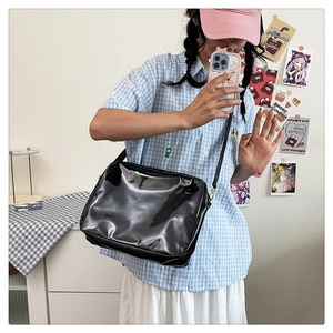 Close-up of minimalist black glossy crossbody bag with a sleek rectangular structure