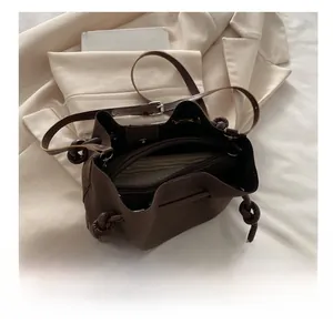 Interior view of deep brown bucket bag showing zippered compartment and drawstring closure
