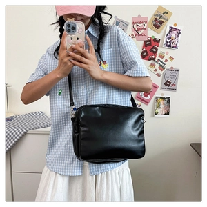 Detail of minimalist black leather crossbody bag with slim strap on a model
