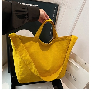 Dettaglio di una grande borsa tote gialla in tela con tracolla regolabile e consistenza morbida