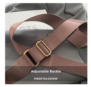 Detail of adjustable metal buckle on brown woven shoulder strap for chic handbag