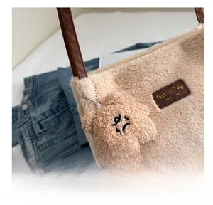 Detail of beige fuzzy shoulder bag with brown leather patch and quirky bear plush charm