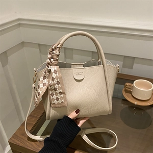 Sac seau beige élégant en cuir grainé avec un foulard à carreaux sur la poignée
