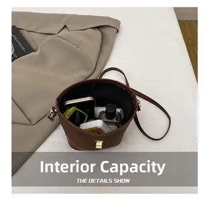 Spacious interior of brown suede bucket bag holding smartphone, sunglasses and perfume