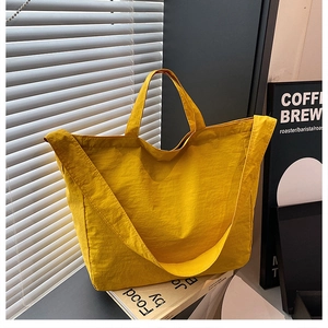Vista dettagliata della borsa tote gialla con ampia tracolla su scrivania minimalista