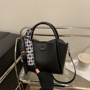 Sac à main minimaliste en cuir noir avec poignée enrubannée et détails dorés élégants