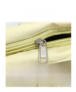Dettaglio ravvicinato della cerniera in metallo liscio sulla borsa da scuola beige