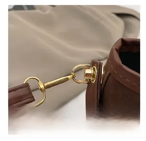Detailed close-up of brown faux leather strap with gold-tone metal spring hook hardware