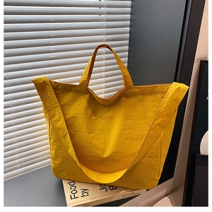 Dettaglio della borsa tote in nylon giallo con tessuto impermeabile e tracolla larga