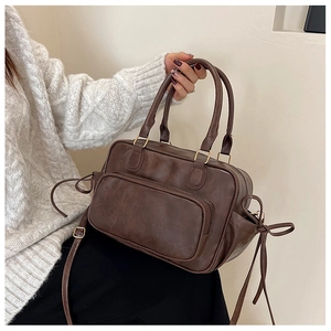Detail of dark brown vintage PU leather Boston bag with side drawstring and top handle