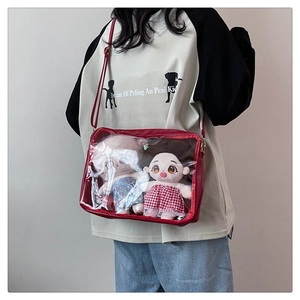Detail shot of the red ita bag featuring a large clear PVC window and plush doll display