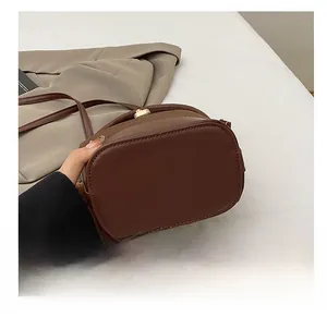 Detailed macro view of the oval wear-resistant bottom on this dark brown bucket bag