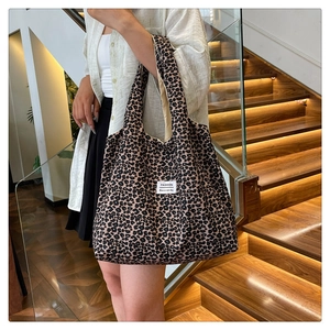 Detail view of large leopard print tote bag with Fashion label on indoor wooden stairs