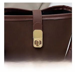 Detail of golden metal twist lock and textured dark brown leather on stylish bucket bag