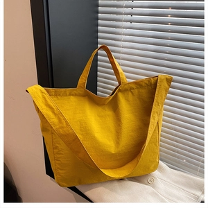 Dettaglio della grande borsa tote in tela giallo brillante con tracolla larga e trama del tessuto