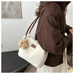 Detail view of white plush tote bag with brown leather straps and cute bear charm pendant