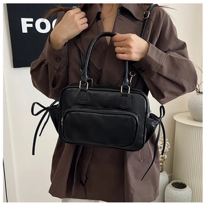 Close-up of black leather bag with refined texture and decorative bow details