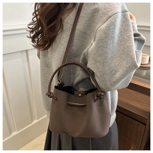 Brown bucket bag detail showing matte texture and drawstring closure on a shoulder strap