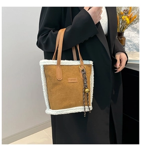 Détail du sac cabas en daim caramel avec bordure en fausse fourrure et breloque