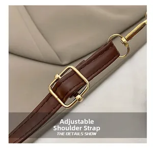 Detail of dark brown leather adjustable shoulder strap with golden metal buckle and spring hook