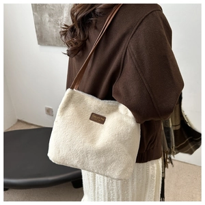 Detail of plush faux fur bucket bag with leather brand tag and adjustable shoulder strap