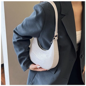 Gros plan d'un sac sous le bras blanc à motif crocodile porté avec un blazer décontracté