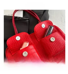 Detail of red crocodile texture handbag with magnetic flap pockets and metallic hardware
