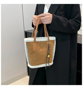 Détail du sac seau en daim marron avec bordure en peluche blanche et patch tendance