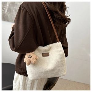 Detail view of white plush faux fur shoulder bag with leather logo tag and bear charm