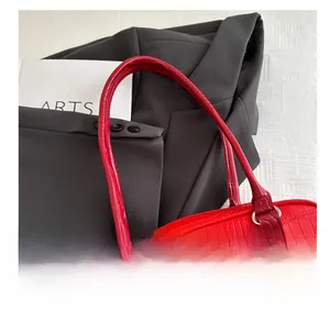 Detail view of red faux crocodile leather handbag strap with silver circular metal rings