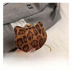 Detail showing leopard print cat-shaped mini bag with gemstone clasp and golden chain strap