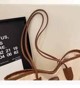 Close-up of durable nylon tote bag featuring brown leather trim and detailed stitching on handle