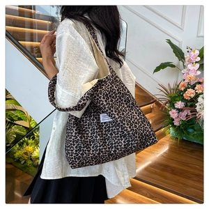 Detailed view of leopard print tote bag worn by model in a stylish indoor setting