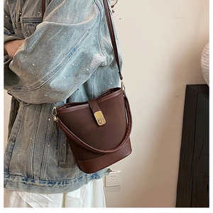 Side view of deep brown bucket bag showing the texture mix and gold metal buckle