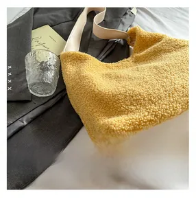 Detail of yellow plush tote bag showing soft texture and cream leather shoulder strap