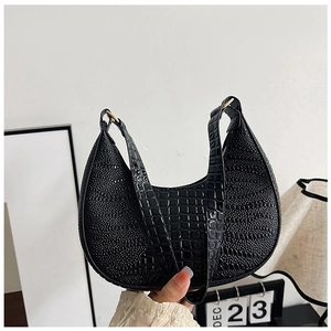 Détail du sac hobo en cuir gaufré crocodile noir avec des accents d'anneaux métalliques
