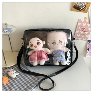 Detail of black ita bag showing transparent PVC window with two 20cm plush cotton dolls
