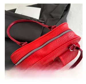 Detail view of red crocodile pattern shoulder bag featuring dual front pockets and metal zippers