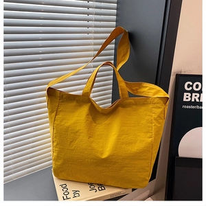 Dettaglio macro della borsa tote gialla in tela capiente con tracolla regolabile e texture