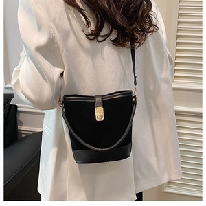 Detail of black suede bucket bag featuring a gold metal twist lock and dual straps