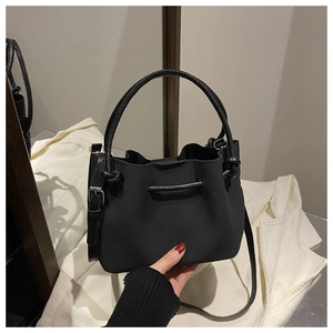 Detail of black drawstring bucket bag with thick round handle and adjustable strap