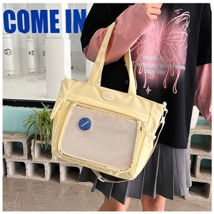 Dettaglio della borsa tote in nylon giallo chiaro con tasca a rete e stemma