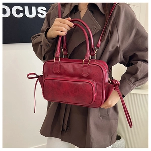 Detail of burgundy vintage leather handbag showing reinforced handles and textured finish