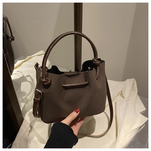 Detail view of deep coffee matte leather bucket bag with tubular handle and shoulder strap