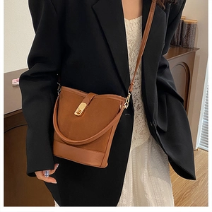 Detail of vintage brown bucket bag showing suede stitching and golden turn-lock closure